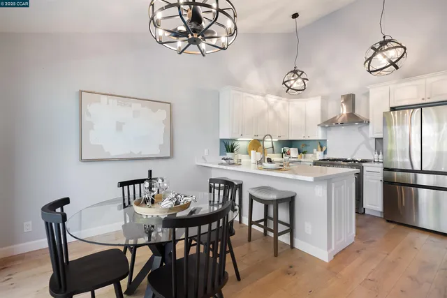 a kitchen with stainless steel appliances granite countertop a dining table chairs and a refrigerator