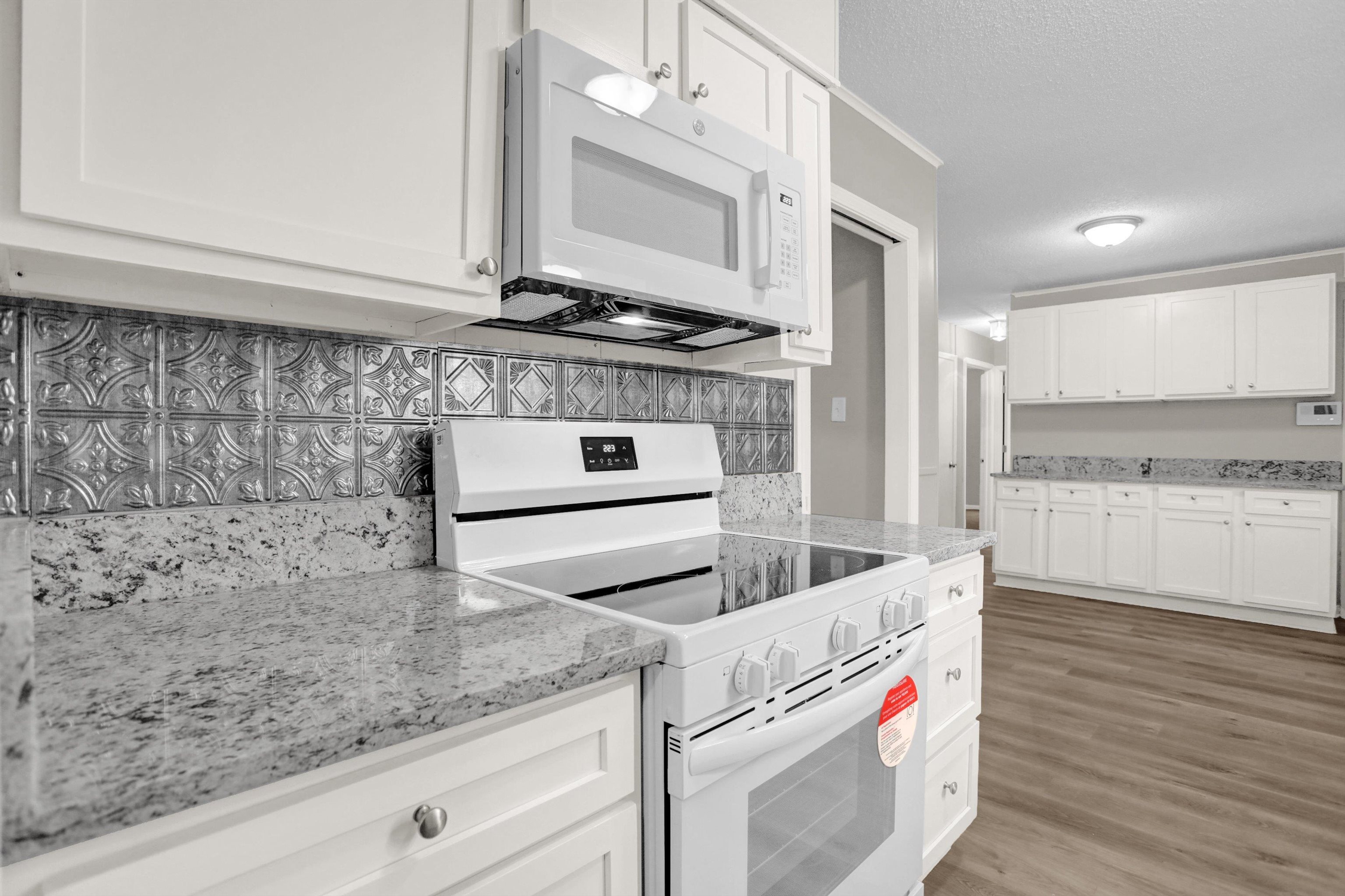 2853 Clearbrook Street Memphis, TN 38118 - Photo 13 of 30 Kitchen featuring white appliances, light stone counters, a textured ceiling, light wood-type flooring, and white cabinetry