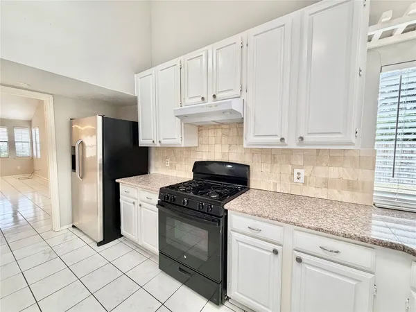 a kitchen with granite countertop white cabinets and stainless steel appliances