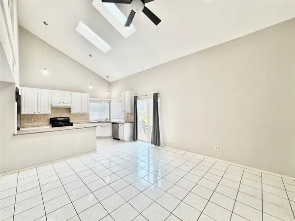 a large white kitchen with a stove a sink dishwasher and a refrigerator with white cabinets