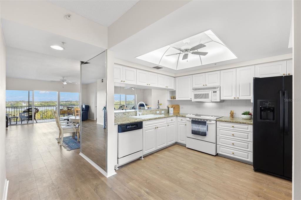 6475 Shoreline Drive, Unit 5403 St. Petersburg, FL 33708 - Photo 16 of 46 a kitchen with white cabinets and stainless steel appliances