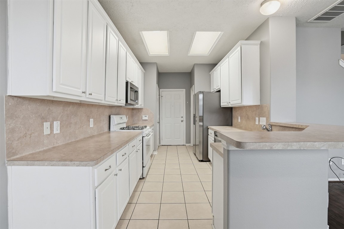 13084 Peppergate Lane Houston, TX 77044 - Photo 4 of 10 a kitchen with stainless steel appliances granite countertop a sink stove and cabinets