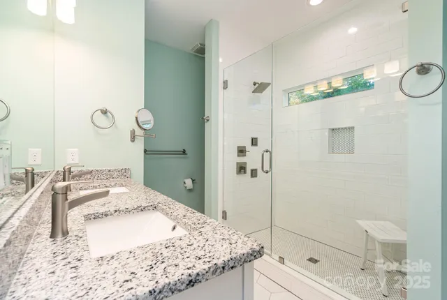 a bathroom with a granite countertop sink a mirror and shower