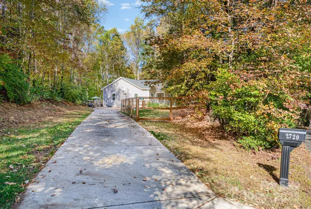 a pathway of a house with yard and a trees