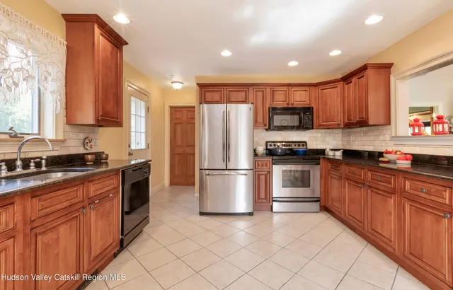 a kitchen with stainless steel appliances granite countertop a stove top oven a sink and a refrigerator