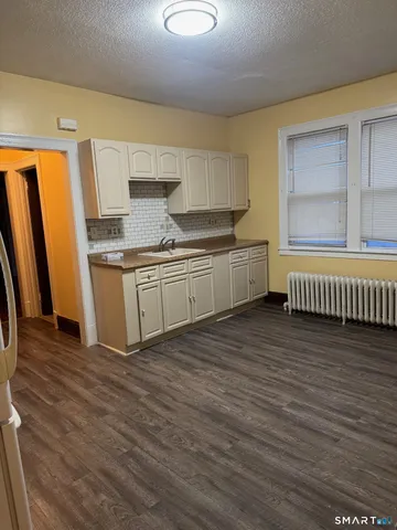 a kitchen with stainless steel appliances granite countertop a sink a stove a refrigerator cabinets and wooden floor