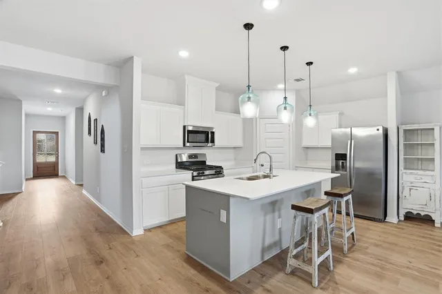 a kitchen with stainless steel appliances kitchen island a refrigerator a stove a sink and a chairs