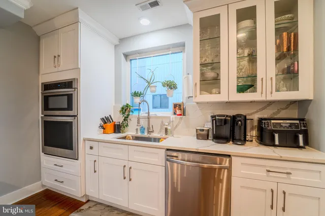 a kitchen with white cabinets and window