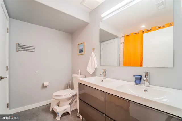 a bathroom with a sink mirror toilet and next to a window