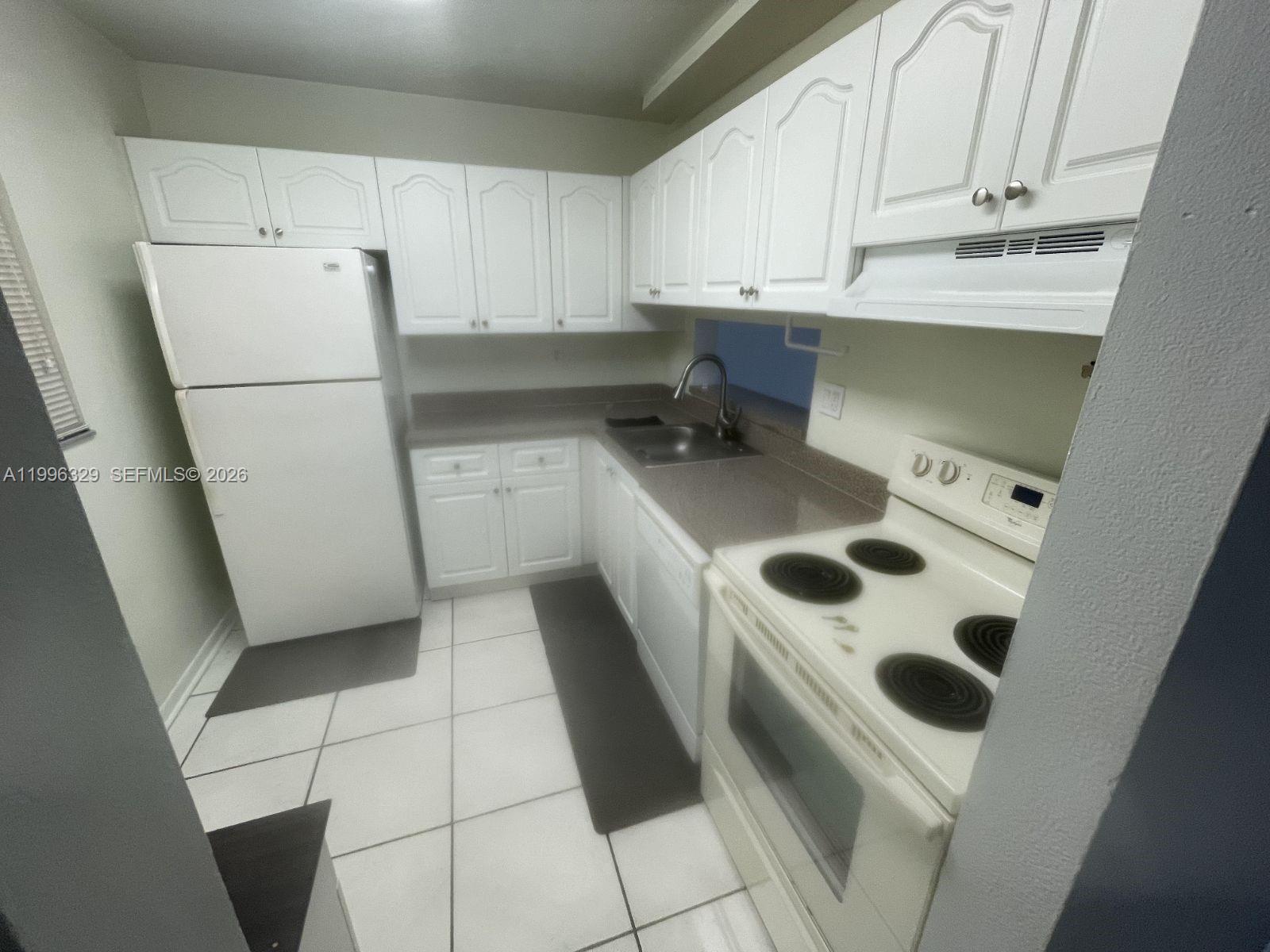 8015 Southwest 107th Avenue, Unit 221 Miami, FL 33173 - Photo 1 of 6 a kitchen with a refrigerator sink and cabinets
