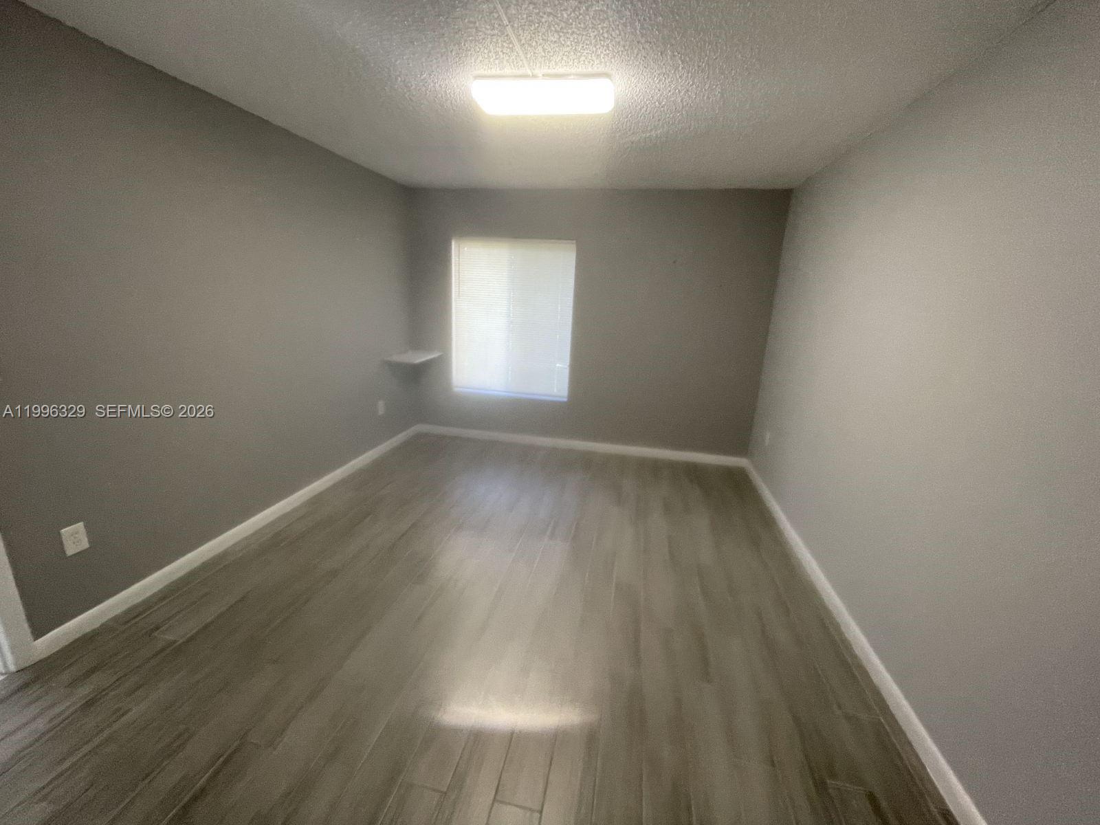 8015 Southwest 107th Avenue, Unit 221 Miami, FL 33173 - Photo 4 of 6 an empty room with wooden floor and windows