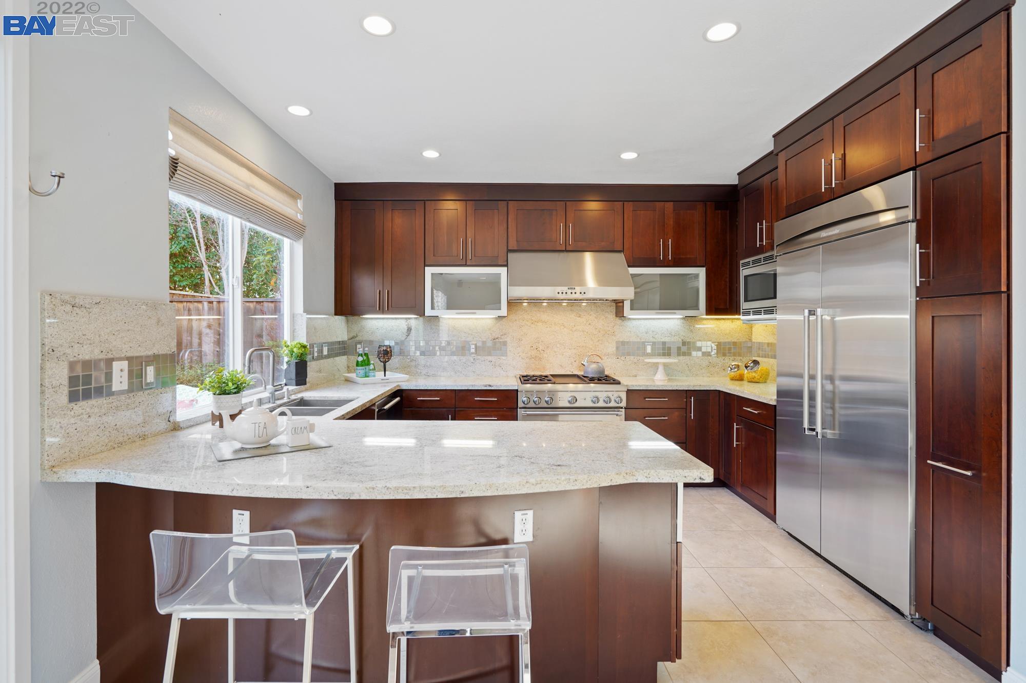 a kitchen with stainless steel appliances granite countertop a sink refrigerator and cabinets