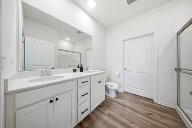 a spacious bathroom with a double vanity sink a mirror and a toilet