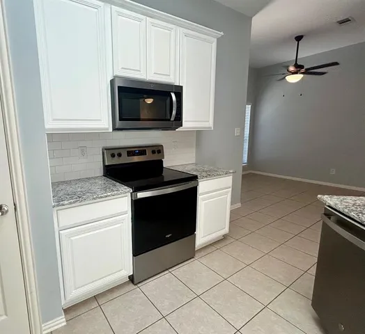 a kitchen with granite countertop white cabinets and black appliances