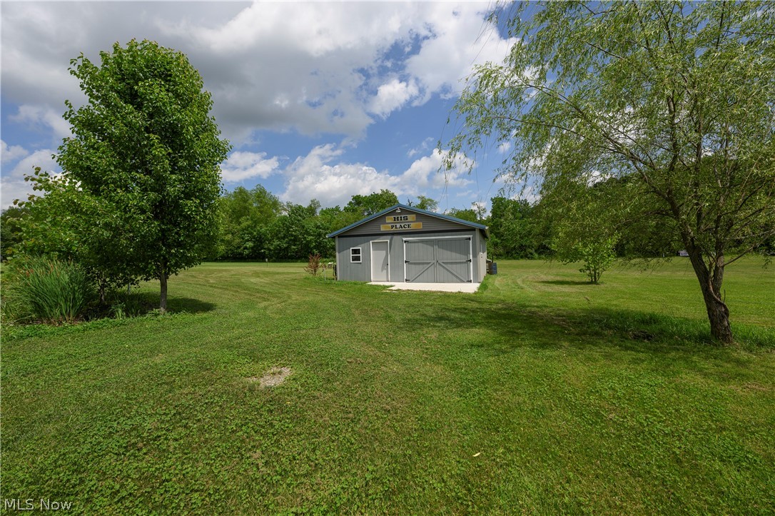 9427 Stonecreek Road Southwest Newcomerstown, OH 43832 - Photo 10 of 29 Detached gray outbuilding featuring a metal roof, double barn doors, and side entry door, surrounded by a expansive green lawn and mature trees
