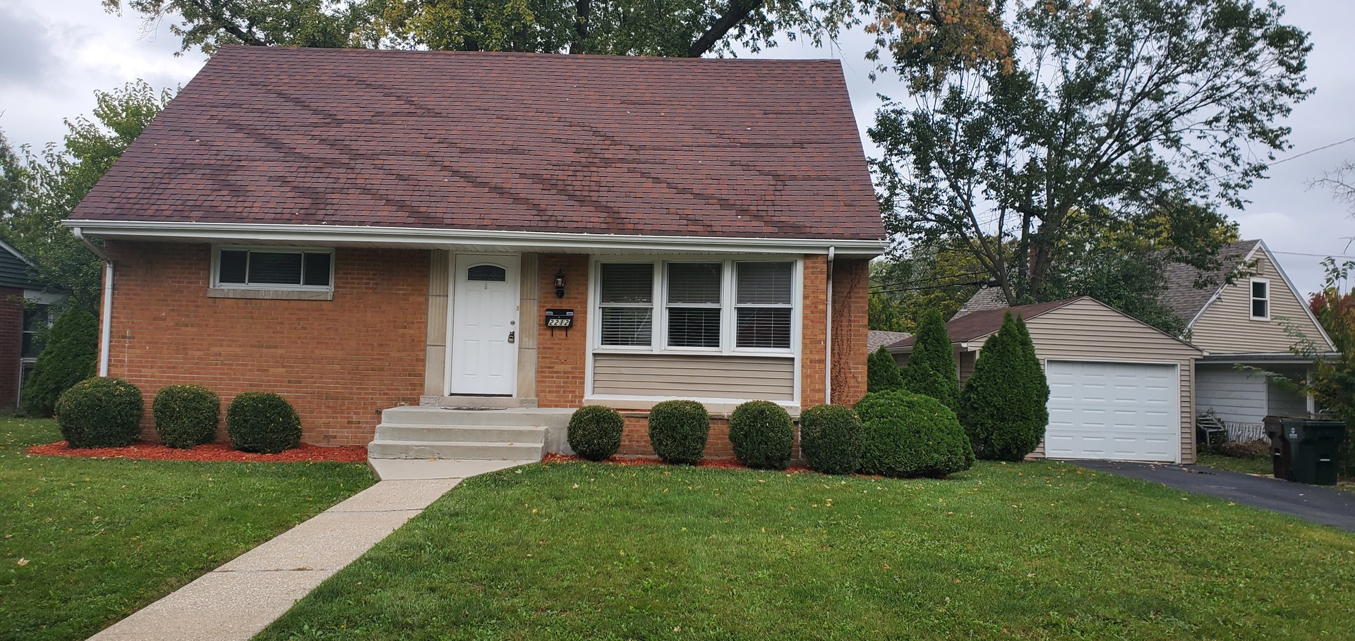 a view of a house with a yard and a large tree