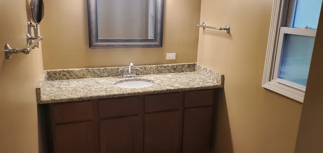 a bathroom with a granite countertop sink and a mirror