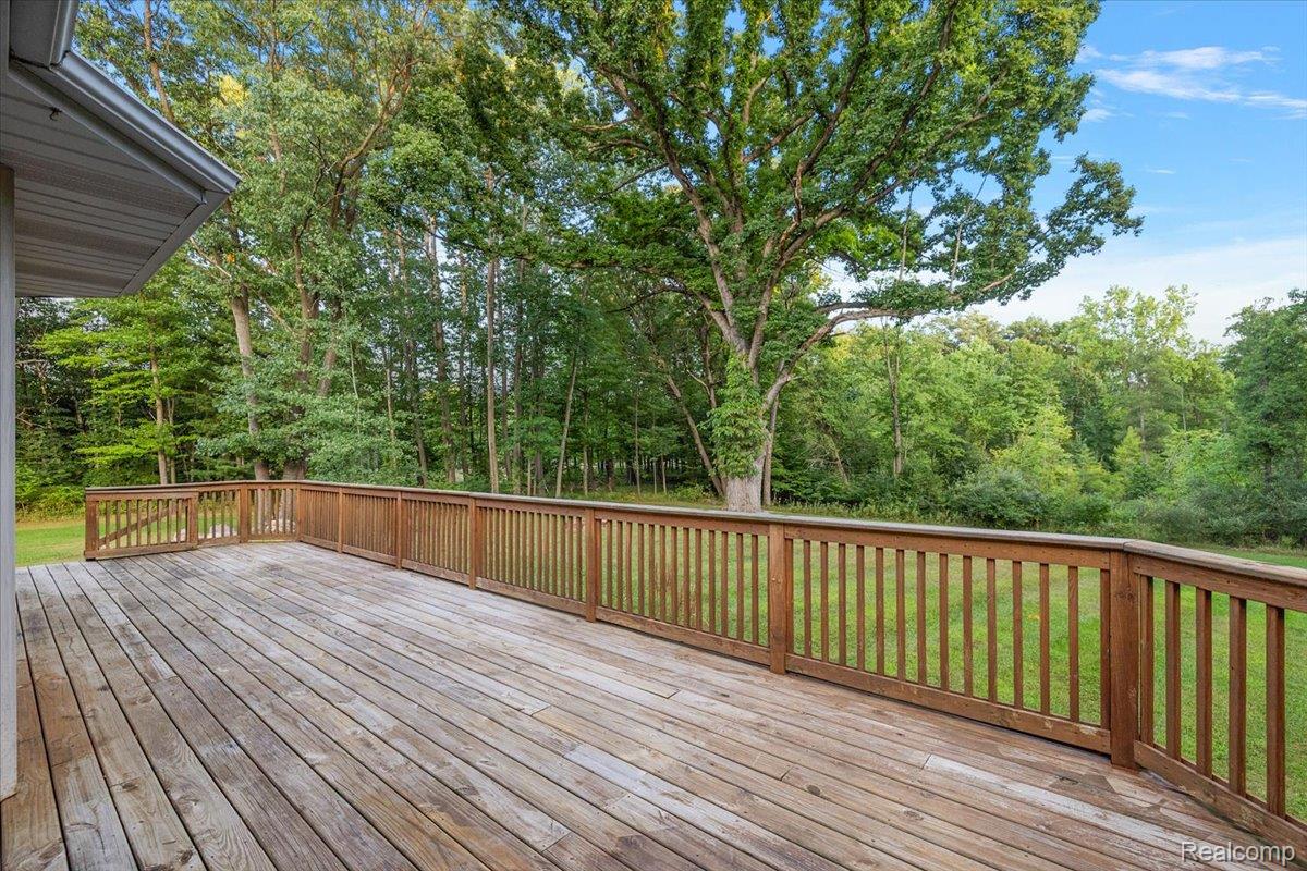 707 West Sutton Road Metamora, MI 48455 - Photo 74 of 84 Expansive wood-plank deck with a wood-railed perimeter, surrounded by mature trees and natural greenery