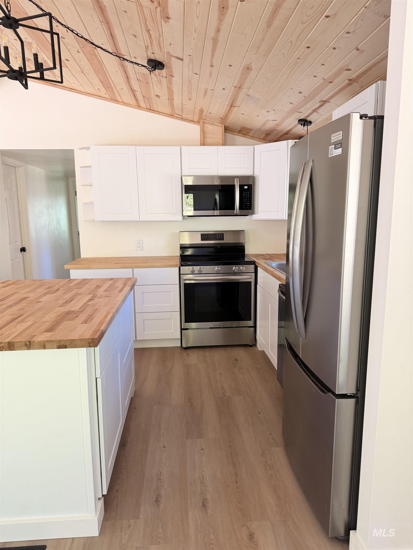 151 View Road Kamiah, ID 83536 - Photo 7 of 49 Kitchen featuring an island, white cabinetry, wood-finish countertops, stainless steel appliances, and a vaulted wood-paneled ceiling