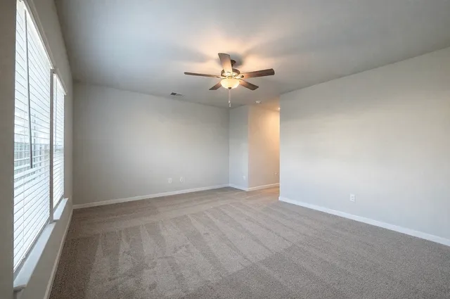 an empty room with windows and fan