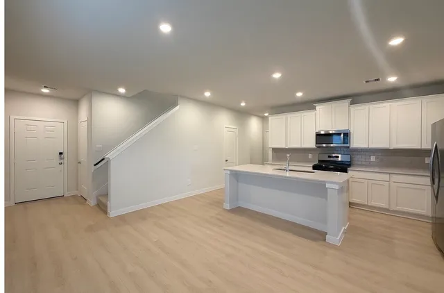 a view of kitchen with center island stainless steel appliances wooden floor and window