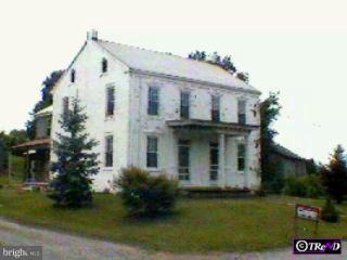 a view of a white house next to a yard with big trees