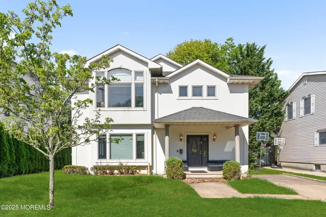 a front view of a house with a yard and trees