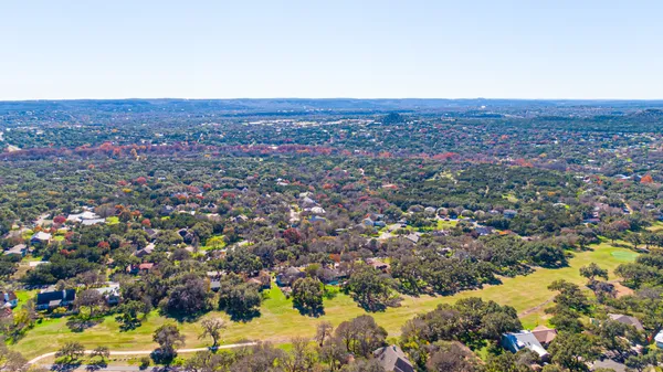 an aerial view of residential houses with outdoor space and trees