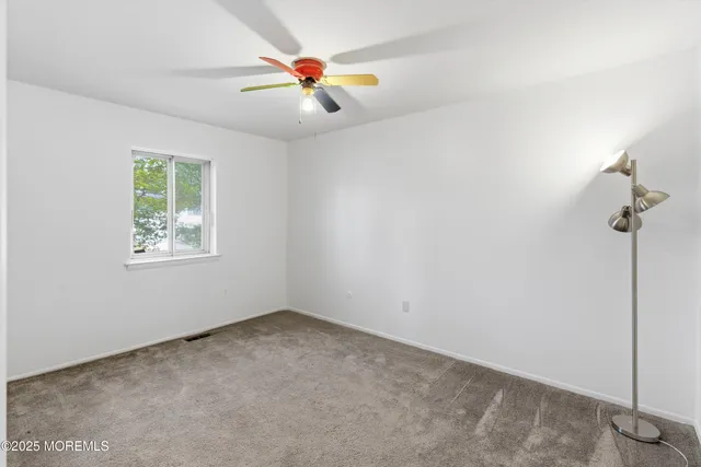 an empty room with windows and fan