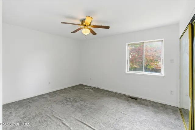an empty room with a window and a ceiling fan