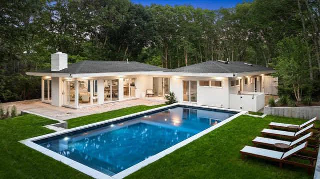 a view of a house with pool backyard and chairs
