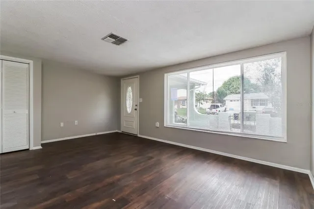 a view of an empty room with wooden floor and a window