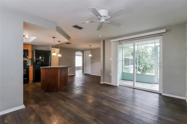 a view of a big room with wooden floor a ceiling fan and windows