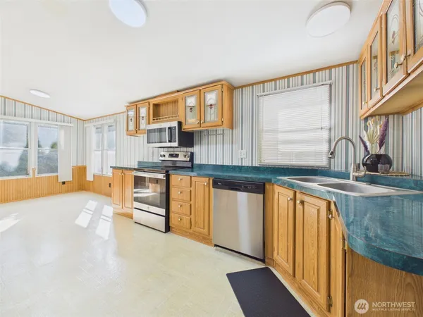 a large kitchen with stainless steel appliances granite countertop a sink and a stove next to a window