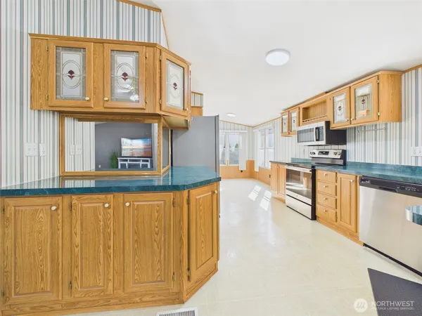 a kitchen with stainless steel appliances granite countertop a refrigerator a stove and a wooden cabinets