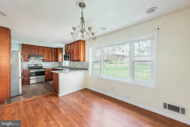 a kitchen with stainless steel appliances granite countertop a stove top oven a refrigerator a sink dishwasher with a dining table and chairs with wooden floor