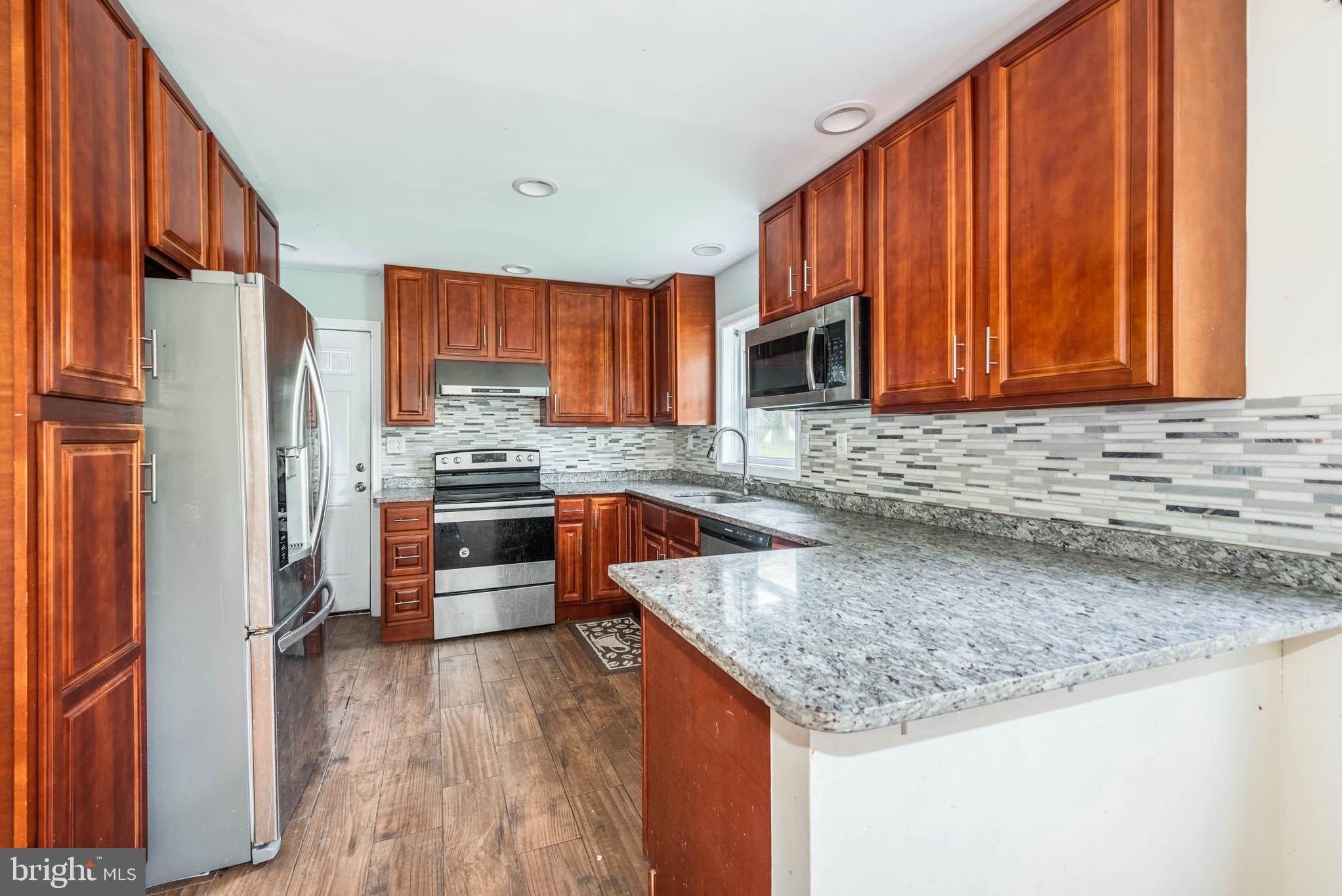 6702 Queens Ferry Road Baltimore, MD 21239 - Photo 7 of 40 a kitchen with stainless steel appliances granite countertop a stove a sink dishwasher a refrigerator and a microwave oven