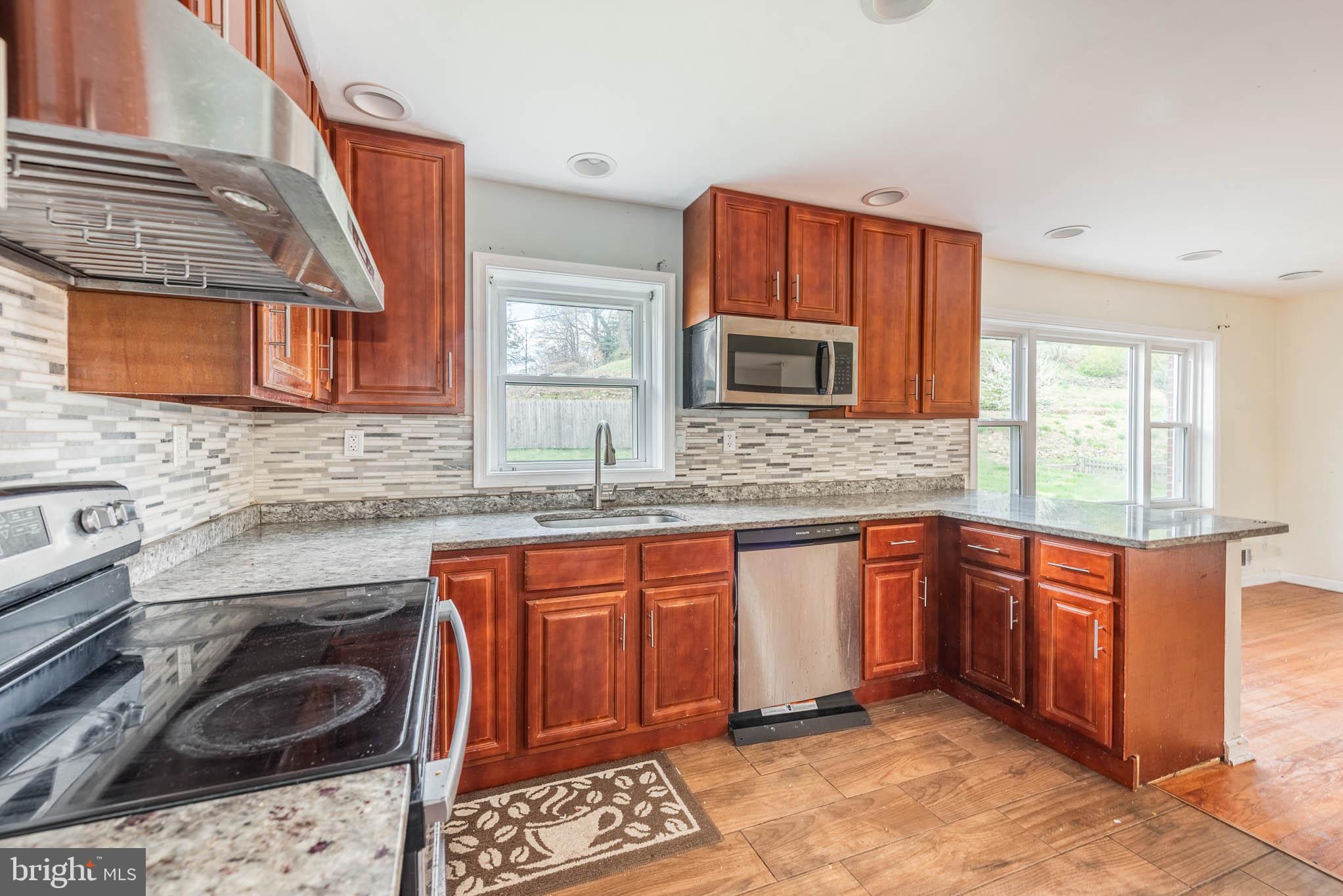 6702 Queens Ferry Road Baltimore, MD 21239 - Photo 9 of 40 a kitchen with stainless steel appliances granite countertop a sink stove and cabinets