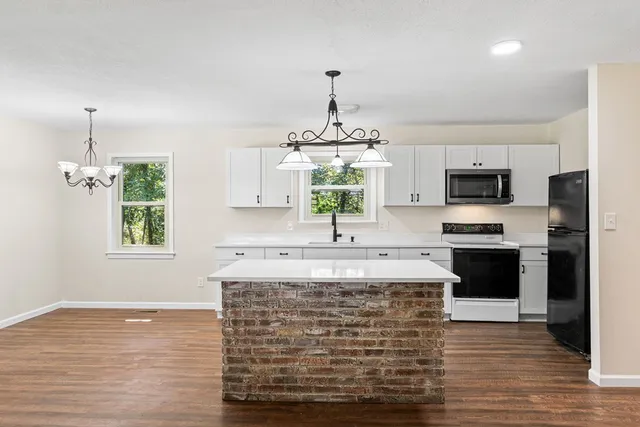 a kitchen with kitchen island granite countertop a stove a oven a sink dishwasher and a flat screen tv