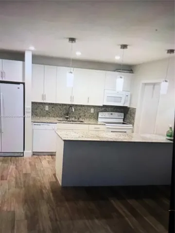 a kitchen with stainless steel appliances granite countertop a sink a stove a refrigerator and white cabinets