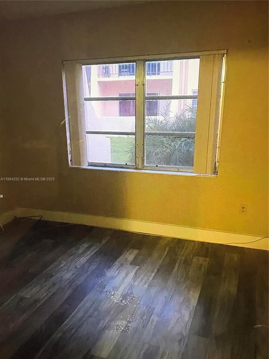 13864 Southwest 90th Avenue, Unit 108LL Miami, FL 33176 - Photo 4 of 10 an empty room with wooden floor and windows