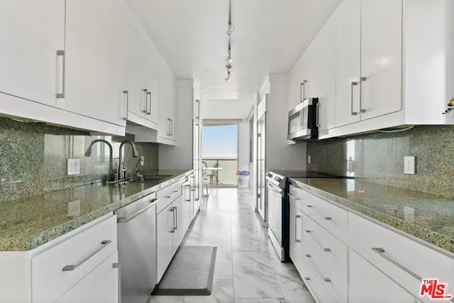 a kitchen with granite countertop a sink a stove and cabinets