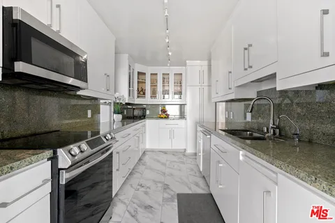 a kitchen with stainless steel appliances granite countertop a stove a sink and a microwave