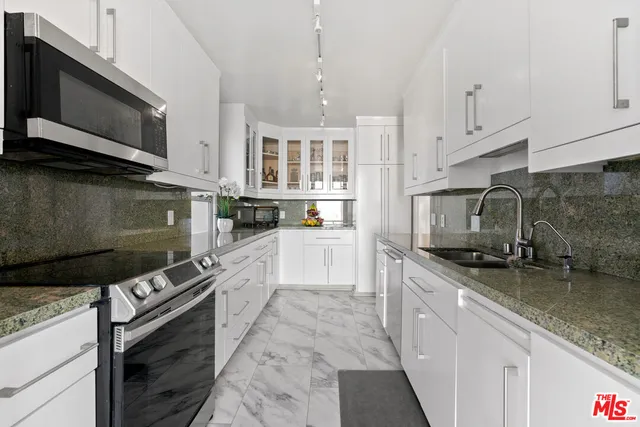a kitchen with stainless steel appliances granite countertop a stove a sink and a microwave