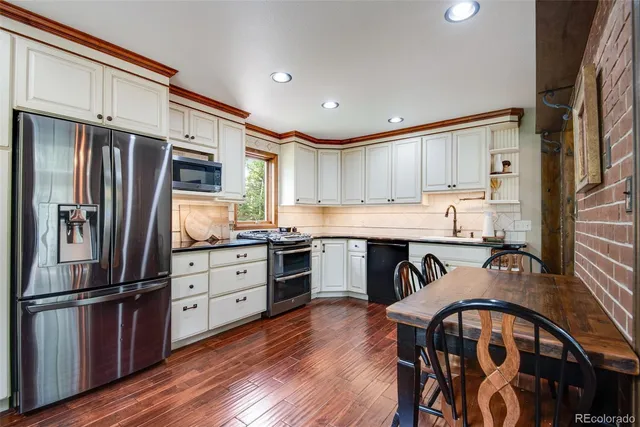 a kitchen with granite countertop a refrigerator stove top oven and cabinets
