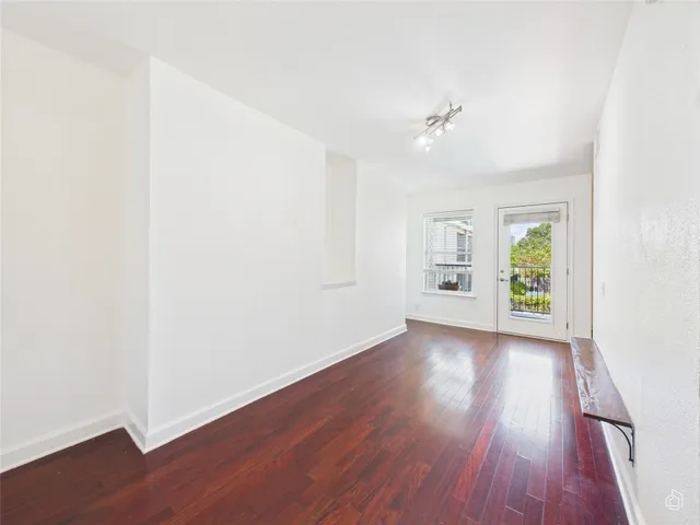 an empty room with wooden floor chandelier fan and windows