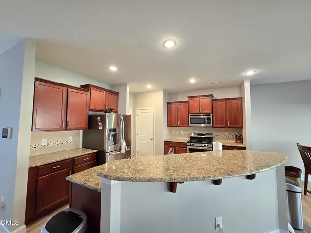 a kitchen with kitchen island granite countertop a sink stove and refrigerator