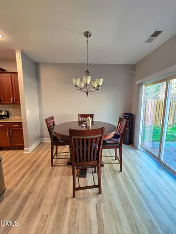 a dining room with furniture a chandelier and wooden floor