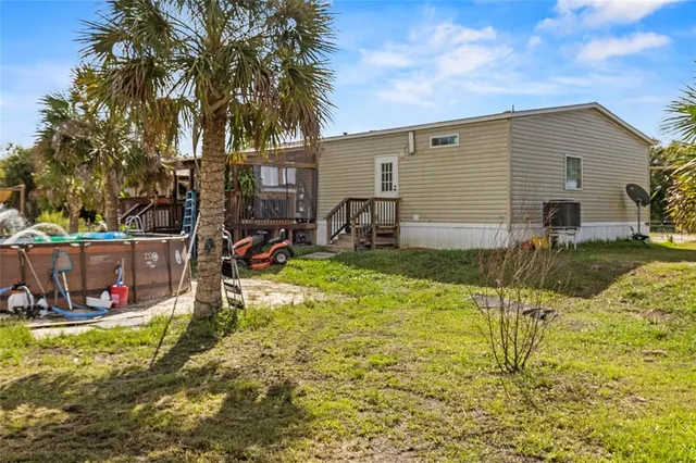 a view of a house with a big yard and palm trees