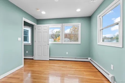 an empty room with wooden floor and windows